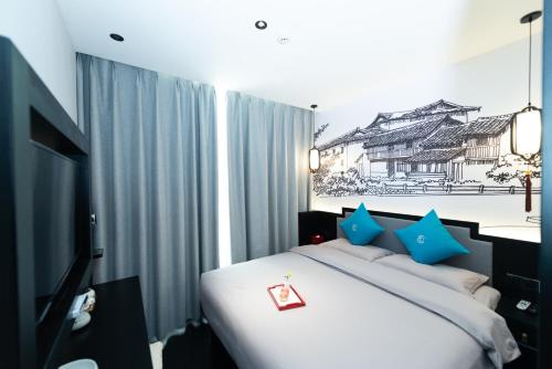 a bedroom with a bed with blue pillows and a tv at Gongxili - Pujian Hotel in Kunming