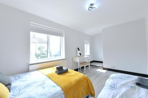 a bedroom with a bed with a yellow blanket and a window at North West London Escape in Mill Hill