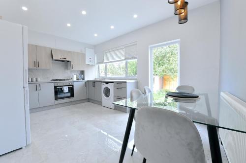 eine weiße Küche mit einem Glastisch und Stühlen in der Unterkunft North West London Escape in Mill Hill