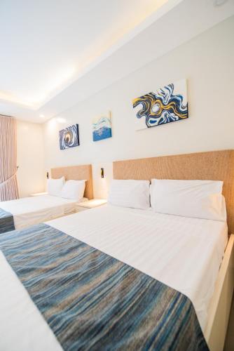 a hotel room with two beds and paintings on the walls at KLM Condotel in Angeles
