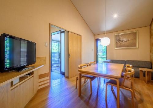 a living room with a dining room table and a television at Kawatana Grand Hotel Otafuku in Shimonoseki
