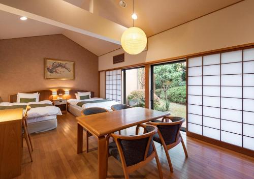 a room with two beds and a table and chairs at Kawatana Grand Hotel Otafuku in Shimonoseki