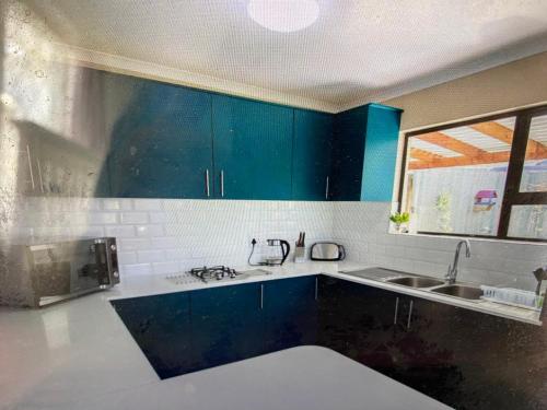 a kitchen with blue cabinets and a sink at Sunrise Bettys Bay in Bettyʼs Bay