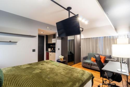 a bedroom with a bed and a couch and a tv at Flat 1111 WCT Berrini Brooklin in Sao Paulo