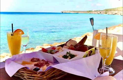 a table with a basket of food and drinks on the beach at VillaDelSol-Ocean Front Resort-Pool-up to 8 Guests-Walk to the Beach in Willibrordus