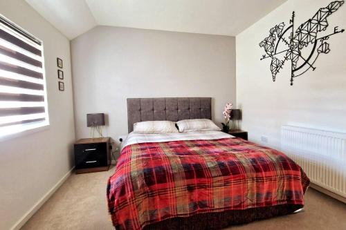 1 dormitorio con 1 cama con manta a cuadros en Luxury 3-Bed House in the Scottish Highlands en Inverness