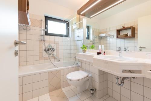 ein Badezimmer mit einem Waschbecken, einem WC und einer Badewanne in der Unterkunft Sporthotel Grafenwald in Daun