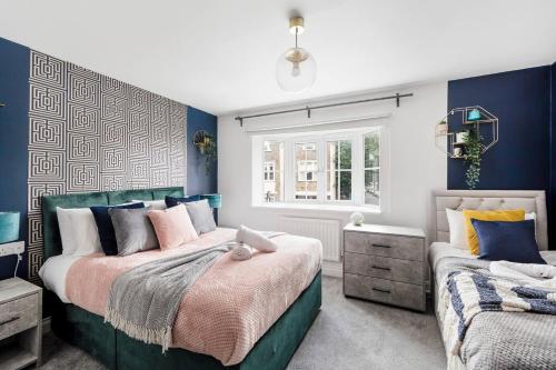 een slaapkamer met twee bedden met blauwe muren en een raam bij Sleek Stylish House 2 Parking - Hot tub & Arcade in Bristol