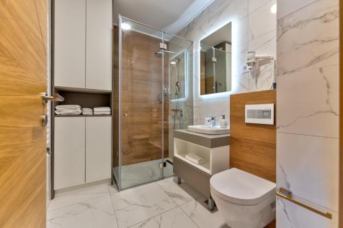a bathroom with a toilet and a glass shower at King's Square Lux apartment Zlatibor 1 in Zlatibor