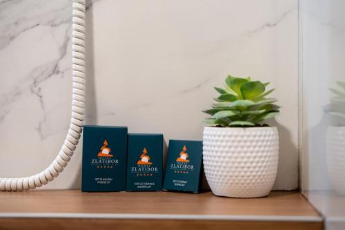four books on a shelf with a potted plant at King's Square Lux apartment Zlatibor 1 in Zlatibor