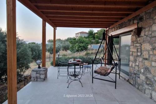 a patio with a swing and a table and chairs at Tepeboz Stone House Tuscany in Karaburun in Karaburun