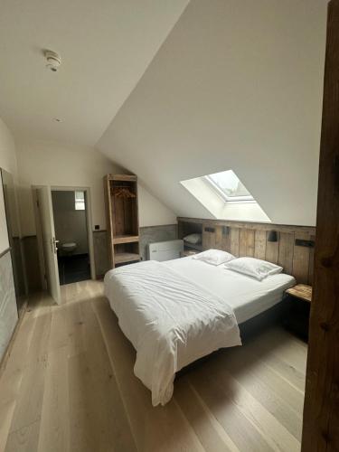 a bedroom with a large white bed with a skylight at Café Coureur Houffalize in Houffalize