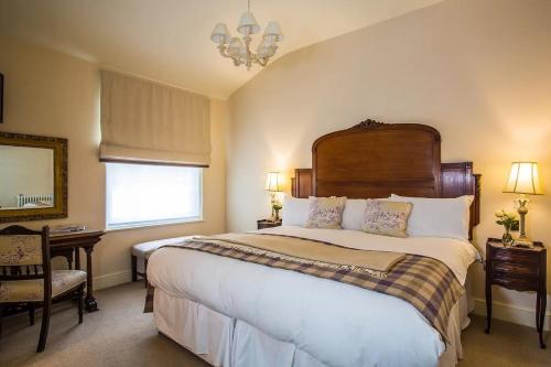 a bedroom with a large bed and a chandelier at The Falcon Hotel in Uppingham