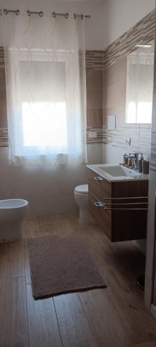 a bathroom with a sink and a toilet and a window at Villa Rosa B&B in Sellia Marina