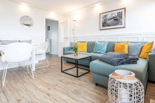 un soggiorno con un divano blu e un tavolo di Dünenhof zum Kronprinzen Penthouse App 115 a Wenningstedt