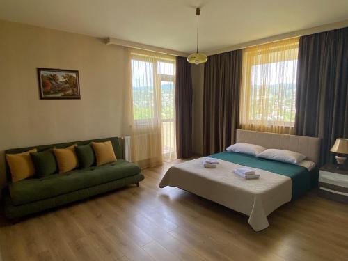 Hotel Legiandro Surami في Surami: غرفة معيشة مع سرير وأريكة