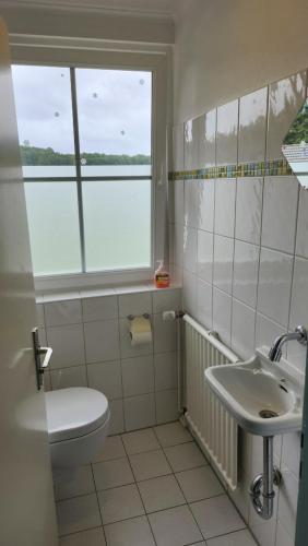 a bathroom with a sink and a toilet and a window at Haus Schönblick in Simmerath