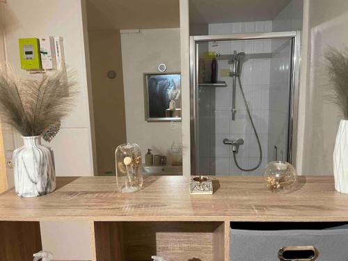 La salle de bains est pourvue d'une douche et d'une table avec un vase. dans l'établissement Studio Lac d'Enghien, à Enghien-les-Bains