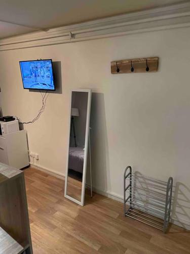 Habitación con espejo y TV en la pared. en Studio Lac d'Enghien en Enghien-les-Bains