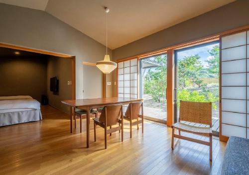 a dining room with a table and chairs and a bedroom at Kawatana Grand Hotel Otafuku in Shimonoseki