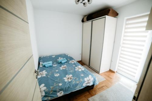 a small bedroom with a bed with a blue blanket at Apartman Ksenija in Vrnjačka Banja