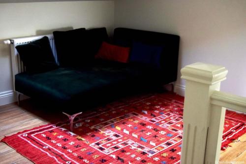 a black couch in a room with a red rug at The Cherriehouse in Gingelom