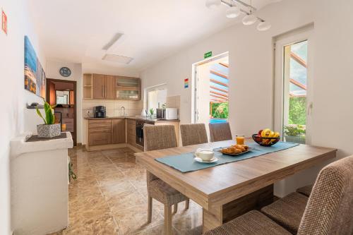 a kitchen and dining room with a wooden table and chairs at Al Rabló Vendégház in Mátrakeresztes