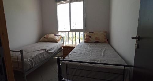 two beds in a small room with a window at Séjour Paisible au Bord de la Nature. in Tangier