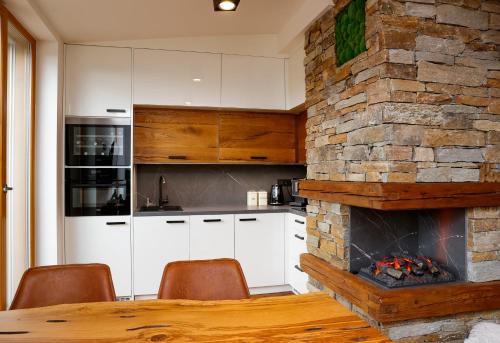 a kitchen with a stone fireplace and a table and chairs at Javor apartmán na Šumavě in Železná Ruda