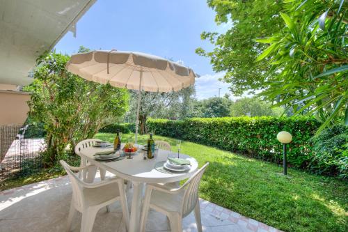 una mesa blanca con sillas y una sombrilla en Casa Perla - Happy Rentals, en Desenzano del Garda