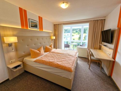 ein Hotelzimmer mit einem Bett, einem Schreibtisch und einem TV in der Unterkunft Marschalls Hotel Am Rennsteig in Neuhaus am Rennweg