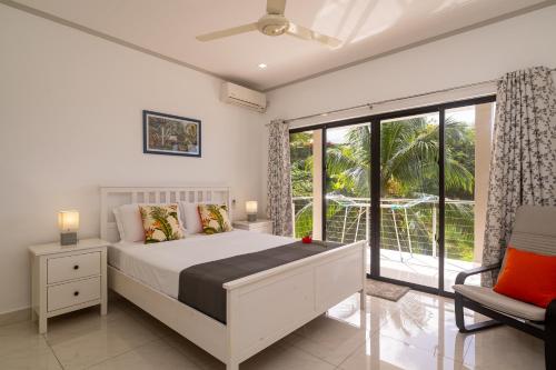 a white bedroom with a bed and a window at East Horizon Self Catering in Au Cap