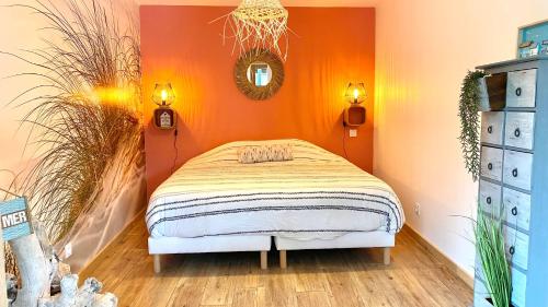 une chambre avec un lit avec un mur orange dans l'établissement La Grange - Gîte de Prestige La Rochelle, à Saint-Médard-dʼAunis