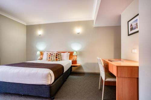 a hotel room with a bed and a desk at Il Mondo Boutique Hotel in Brisbane