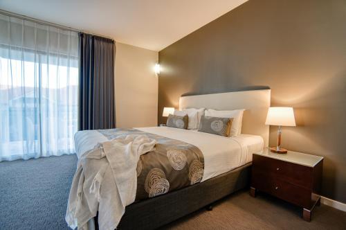 a bedroom with a large bed and a large window at Il Mondo Boutique Hotel in Brisbane