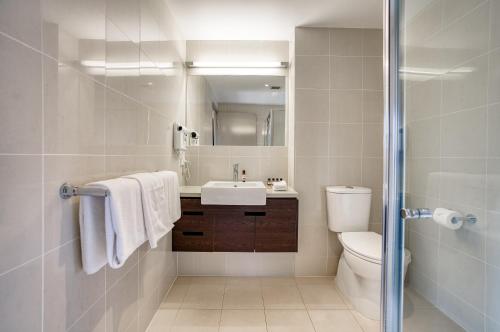 a bathroom with a sink and a toilet and a mirror at Il Mondo Boutique Hotel in Brisbane