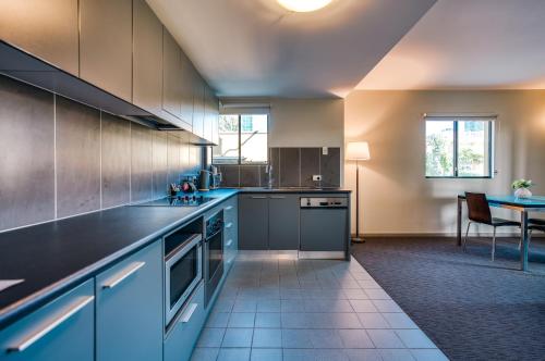 a large kitchen with blue cabinets and a table at Il Mondo Boutique Hotel in Brisbane