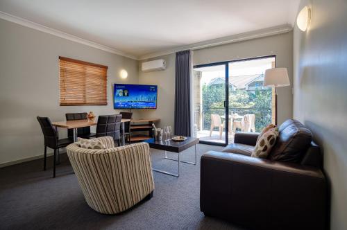 a living room with a couch and a dining room at Il Mondo Boutique Hotel in Brisbane