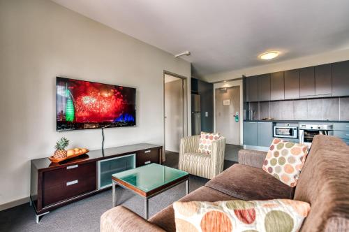 a living room with a couch and a tv at Il Mondo Boutique Hotel in Brisbane