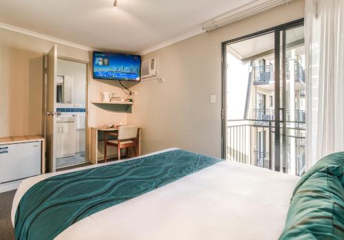 a bedroom with a bed and a tv on the wall at Il Mondo Boutique Hotel in Brisbane