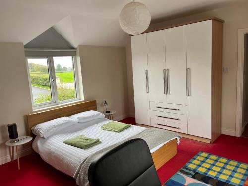 a bedroom with a large bed with a chair and a window at Alexandria House in Donaghadee