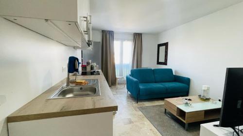 une cuisine avec un évier et un canapé bleu dans l'établissement Joli 2 pièces tout confort Paris Parc des expositions Villepinte, à Villepinte