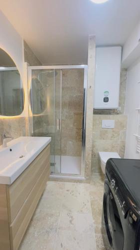 a bathroom with a shower and a sink and a washing machine at Joli 2 pièces tout confort Paris Parc des expositions Villepinte in Villepinte