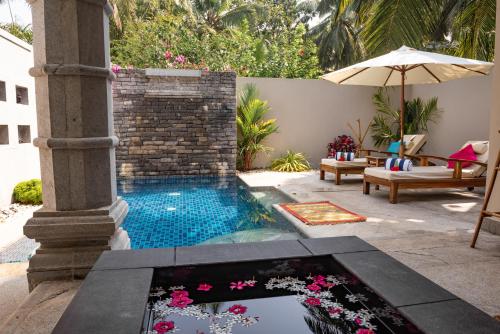 a swimming pool in a patio with an umbrella at Neeleshwar Hermitage in Nīleshwar