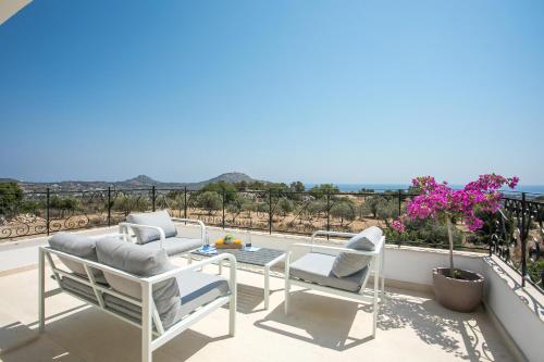 a patio with chairs and a table on a balcony at Exclusive Olive & Herb Villa, Mountain to Sea Views, Rhodes in Afantou