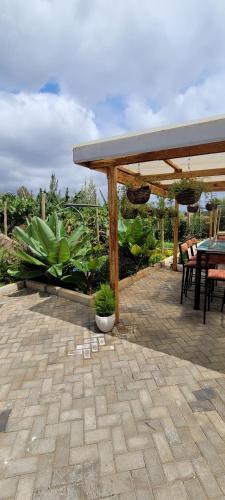 un patio con una mesa y un pabellón con plantas en The Cot, en Kitengela 