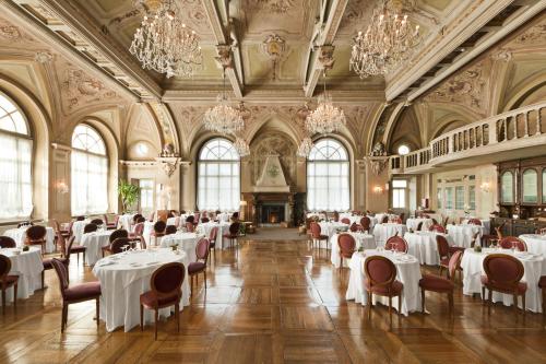 a dining room with white tables and chairs and chandeliers at QC Grand Hotel Bagni Nuovi in Bormio