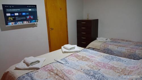1 dormitorio con 2 camas y TV en la pared en LIBERATA en Esquel