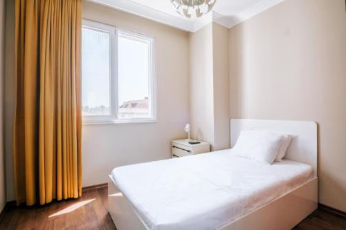 ein Schlafzimmer mit einem weißen Bett und einem Fenster in der Unterkunft Lovely Flat w Balcony 10 min to Moda Coast in Istanbul