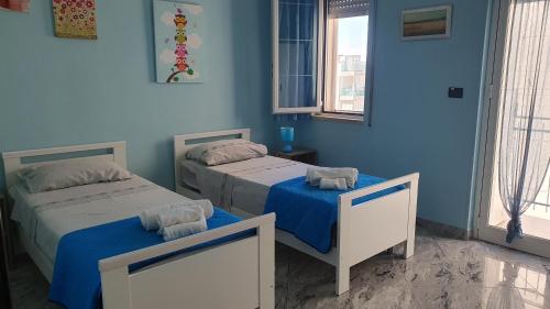 Dos camas en una habitación con paredes azules. en soleada, en Monopoli